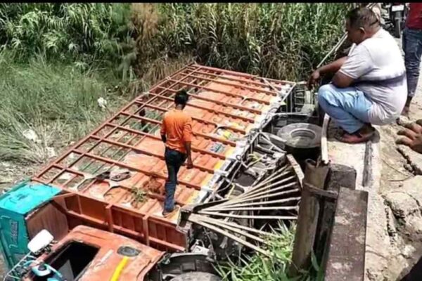 मालन नदी के जर्जर पुल पर टूटी रेलिंग के पास नदी में गिरा ट्रक, प्रशासनिक बचाव कार्य चल रहा है।